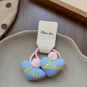 Détail de chouchous cœur en tissu bleu avec broderie Love jaune et petits pompons