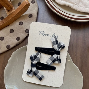Detail of velvet and checkered bow hair clips on a premium brand display card