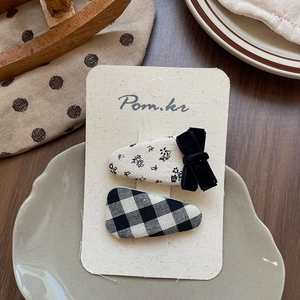Detail view of Korean style floral bow and checkerboard fabric hair clips on a card