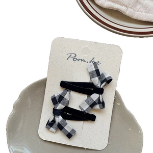 Pair of retro black velvet and checkered bow hair clips on a premium display card