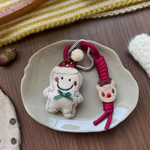 Dettaglio del portachiavi natalizio in peluche a forma di omino di pan di zenzero con fiocco