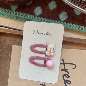 Détail de barrettes à cheveux ours en tricot rose sur plateau en bois rustique