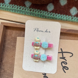Detalle de pinzas de terciopelo rosa con gatos de dibujos y pompones de malla azul