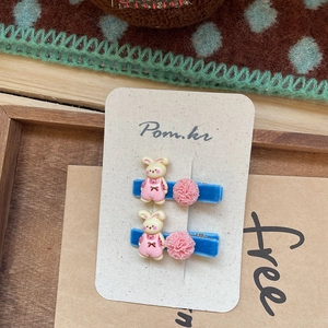Detalle de pinzas para el pelo de terciopelo azul con pompones rosas y dijes de conejo