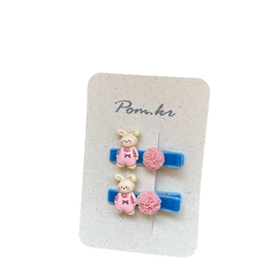 Horquillas estilo coreano con pompón rosa y conejo sobre base de terciopelo azul