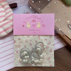 Detail of silver elastic hair ties with heart-shaped pearls on a cute pink card
