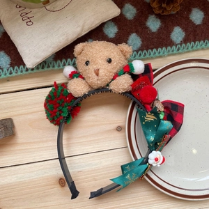 Detail of Christmas headband with plush bear, plaid bow, and festive holiday decorations