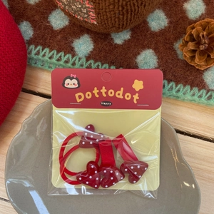Détail de barrettes à pois rouges en forme de cœur et chouchou dans un plat en céramique