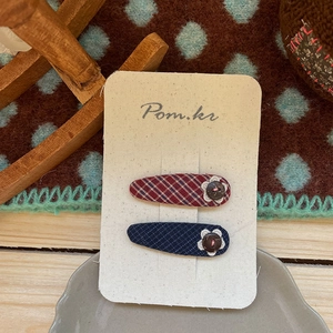 Détail de barrettes à carreaux rouge vin et bleu marine sur carte de support