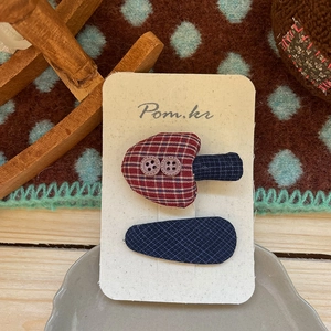 Détail d'une pince à cheveux champignon et d'une barrette en tissu bleu sur carte