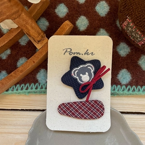 Détail d'une pince à cheveux à carreaux faite main avec broderie ours et étoile en tissu