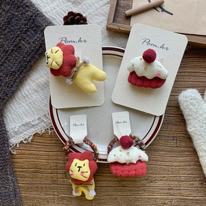 Detailed set of handmade cloth lion and cupcake hair clips and ties in a ceramic dish