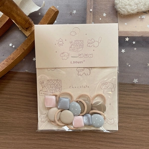 Detail of soft fabric hair ties in earth tones with cute cartoon animal packaging