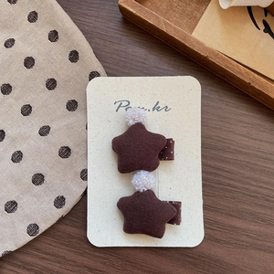 Detail of brown star hair clips with plush balls and polka dot fabric on wooden background