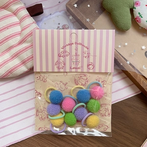 Detail von bunten Macaron Plüschball Haargummis Set in Vintage Cartoon Verpackung