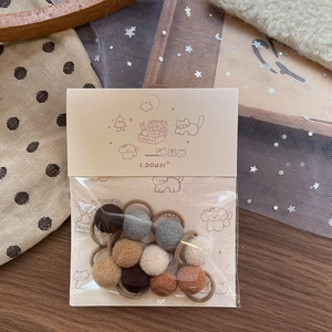 Detail von Plüsch-Haargummis in Braun auf gemütlichem Stoffhintergrund in Verpackung