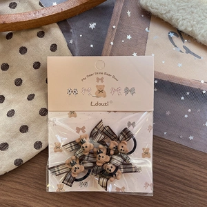 Detail von zwei braunen Bären- und Karo-Haargummis in eleganter Geschenkverpackung