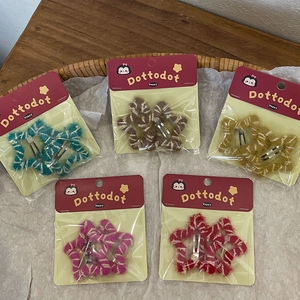 Handmade plush star hair clips for kids in five colors on a wooden and paper background