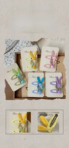 Detailed set of 5 floral fabric bunny ear hair clips with soft pom-poms on a card