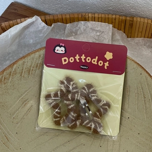 Detailed view of handmade star-shaped hair clips with striped knit fabric on a ceramic plate