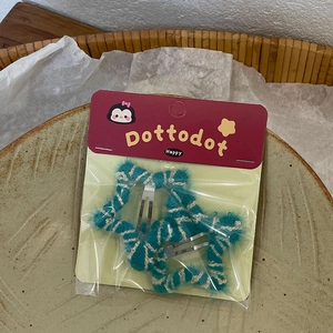Detail of star-shaped plush hair clips with blue and white pattern on ceramic plate