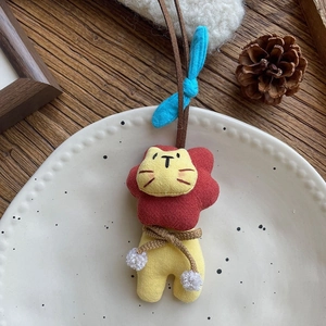 Ciondolo leone in tessuto fatto a mano con ricami rossi e gialli e fiocco blu decorativo
