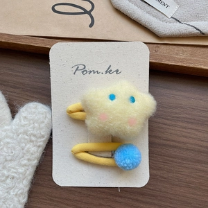 Détail de la barrette étoile en peluche jaune et du pompon bleu sur une carte