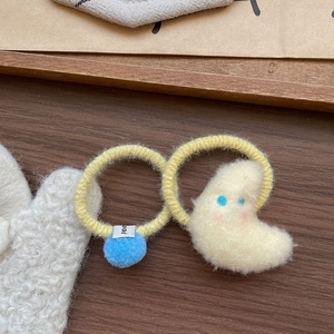 Gros plan d'élastiques à cheveux en peluche avec pompon bleu et personnage de lune jaune