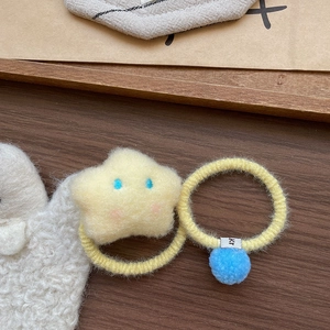 Détail d'élastiques en peluche étoile et boule bleue sur fond de bois chaleureux