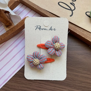 Detail of plaid flower hair clips featuring blue and red houndstooth fabric texture