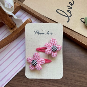 Detail of pink houndstooth flower hair clips with checkered center on display card