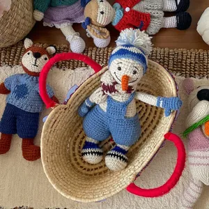 Handmade wool knitted snowman and animal dolls in a rustic woven basket setup