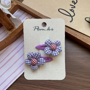 Detail of sweet floral hair clips with purple plaid fabric petals and a safe cloth wrap
