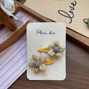 Detail of yellow houndstooth fabric flower hair clips on a white presentation card