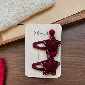 Detail of red star-shaped felt hair clips with pink stitching on display card