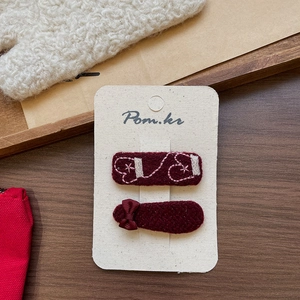 Detail view of handmade wine red fabric hair clips with ribbon bow and white embroidery