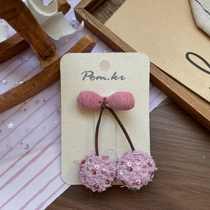 Détail de la pince à cheveux cerise à paillettes roses sur carte avec décor de cheval en bois