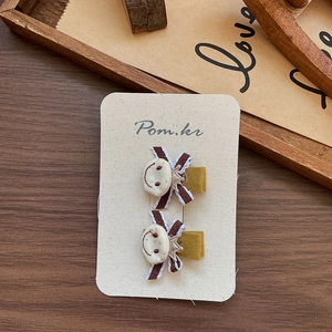 Detailed pair of fabric bear hair clips with striped bows on a wooden display