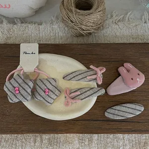 Détail du lot de 5 barrettes à cheveux lapin rose et nœud sur un plateau en bois