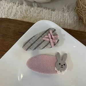 Détail de la pince lapin en velours rose et épingles à nœud gris dans un plat