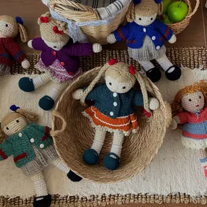 Handmade crochet wool dolls in various colorful knitted outfits on a rustic woven mat