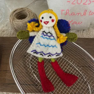 Detail of handmade wool felt girl doll with yellow braids and floral dress on a metal basket