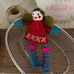 Close-up of handmade wool felt angel girl doll with red dress and green wings hanging charm