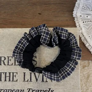 Close-up of a black and blue plaid scrunchie on a vintage book with lace background