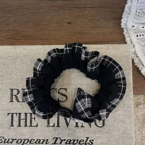 Detail of checkered scrunchie with lace and black resin bead on a vintage book