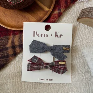 Detail view of plaid and solid fabric bow hair clips with gold engraved metal plates