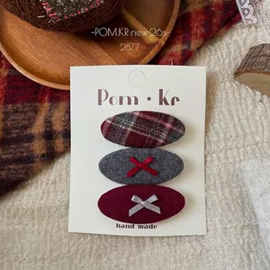Detail view of three plaid and velvet bow hair clips on a white display card in retro style