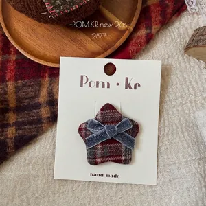 Detail of star-shaped plaid fabric hair clip with blue glitter bow on display card