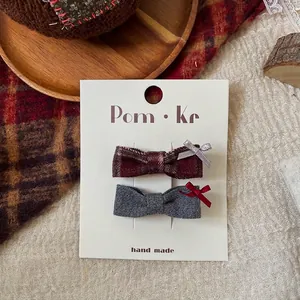 Detail of red plaid and grey fabric bow hair clips set on a vintage display card