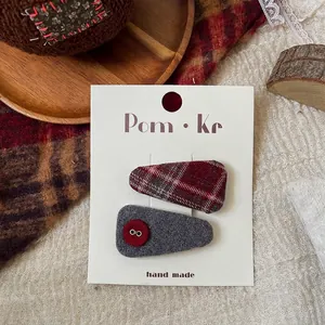 Detail of red plaid and grey tweed bow hair clips on a handmade presentation card